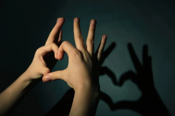 Handen gevormd hart op donker — Stockfoto