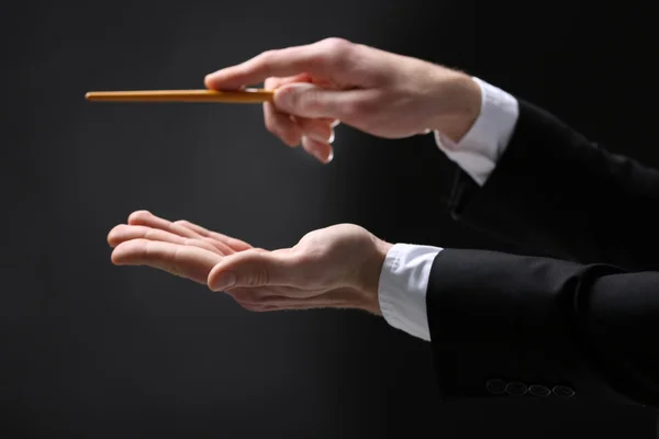 Music conductor directing with baton on black background, close up — Stock Photo, Image