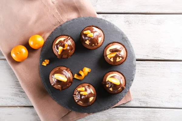 Смачні кекси зі скибочкою мандарина та шоколаду на тарілці на світлому дерев'яному фоні — стокове фото