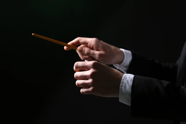 Music conductor directing with baton on black background, close up — Stock Photo, Image