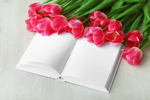 Pink fresh tulips and notebook on the white table, close up — Stock Photo, Image