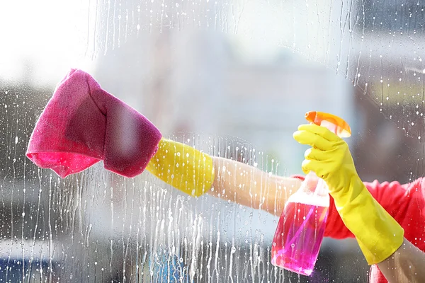 Mulher em uma luva de borracha janela de limpeza com esponja e detergente, de perto — Fotografia de Stock