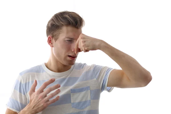 Young blonde man pinching his nose because of the stench, isolated on white — Stock Photo, Image