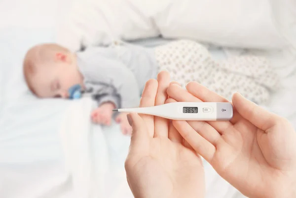 Schlafendes Baby und Hand mit Thermometer — Stockfoto