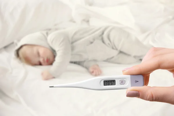 Sleeping baby and hand with thermometer — Stock Photo, Image