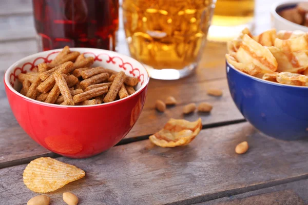 Bira ve ahşap masa snacks ile kase kupalar — Stok fotoğraf