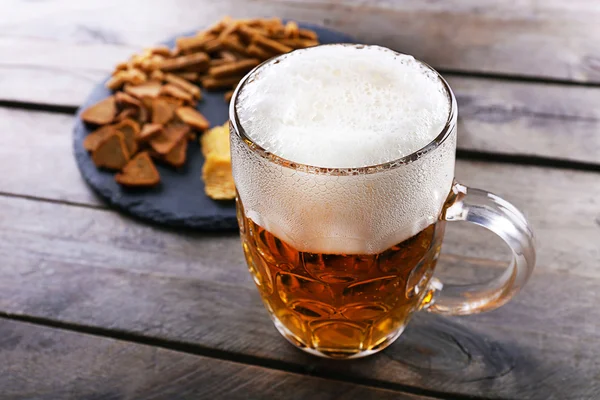 Mok van bier en snacks op houten tafel — Stockfoto