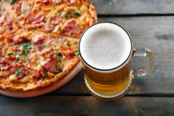 Lekkere pizza en bier glas op houten tafel liggen, close-up — Stockfoto