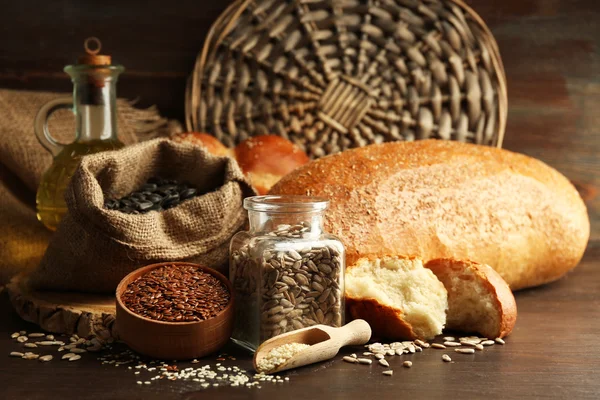 Composition of seeds , bread, buns and oil on wooden table background, closeup — Stock Photo, Image
