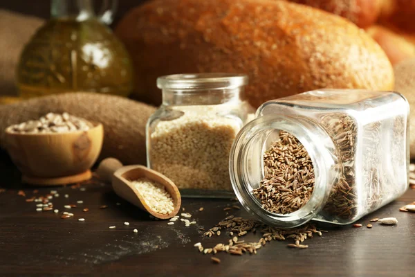 Sammansättningen av frön i banker, bröd, bullar och olja på trä bakgrund, närbild — Stockfoto