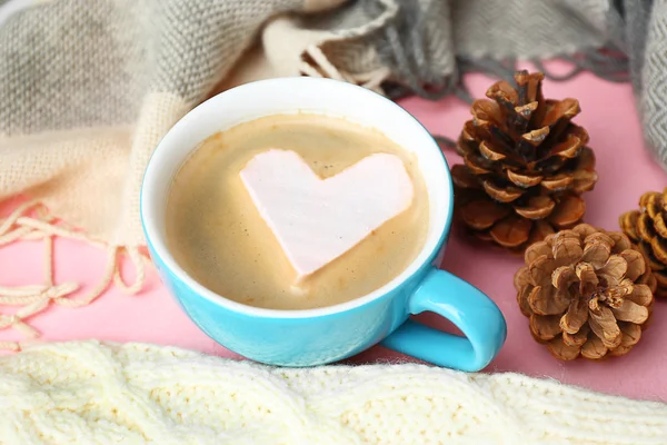 Xícara de cappuccino quente com marshmallow coração e roupas quentes no fundo rosa, close-up — Fotografia de Stock