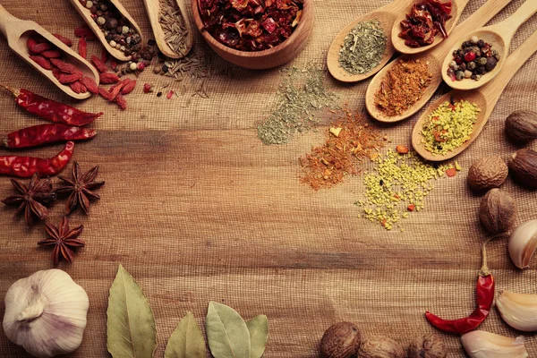 Assorted spices in spoons on wooden table, top view — Stock Photo, Image