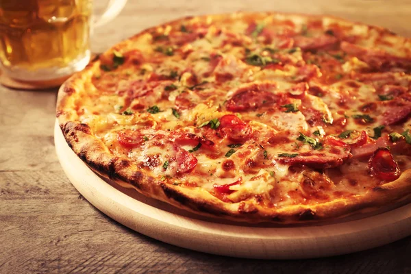 Delicious pizza  and glass of beer are on wooden table, close up — Stock Photo, Image