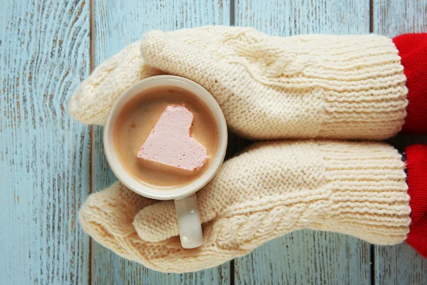 Manos en manoplas sosteniendo taza — Foto de Stock