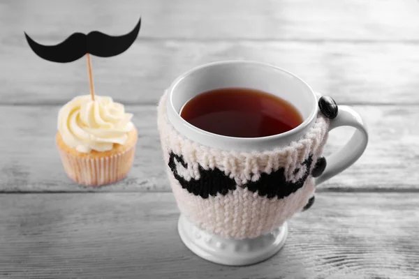 Delicioso magdalena creativa con bigote y taza de té en la mesa de madera — Foto de Stock