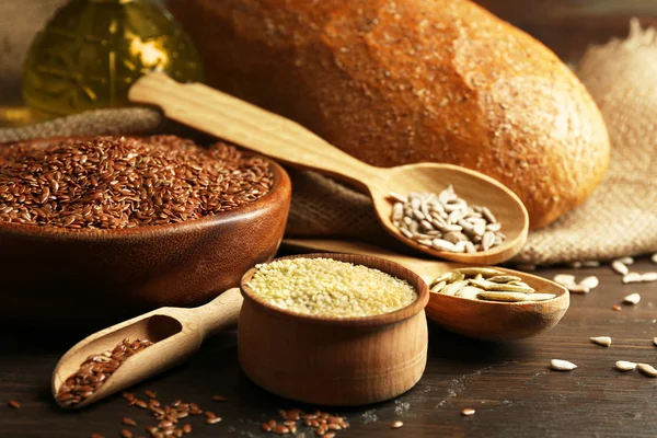 Various seeds with bread and oil on wooden table background, closeup — Stock Photo, Image