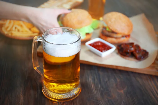 Glazen mok light bier met snacks op donkere houten tafel, close-up — Stockfoto