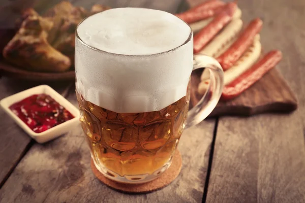 Glass of beer, chicken wings and grilled sausages on wooden table, close up — Stock Photo, Image