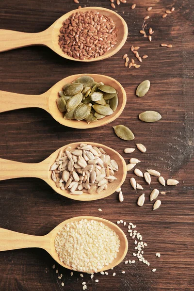 Sesam, Flachs, Kürbis und Sonnenblumenkerne in Holzlöffeln auf dem Tisch, Nahaufnahme — Stockfoto