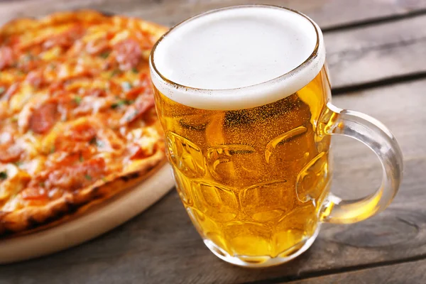 Вкусная пицца и стакан пива на деревянном столе, закрыть — стоковое фото