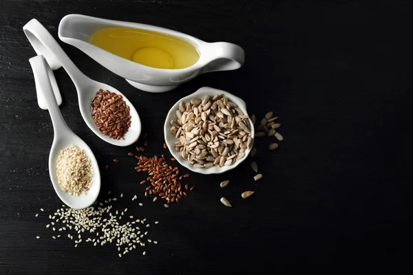 Verschillende soorten zaden en olieverf op houten tafel — Stockfoto