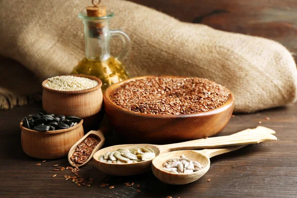 Flax, sesame, pumpkin and sunflower seeds with oil on wooden table background, closeup — Stock Photo, Image