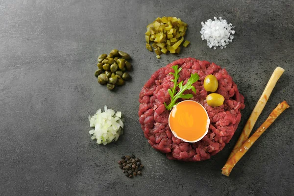 Tartare de boeuf servi avec des bâtonnets de pain sur une surface grise, vue sur le dessus — Photo