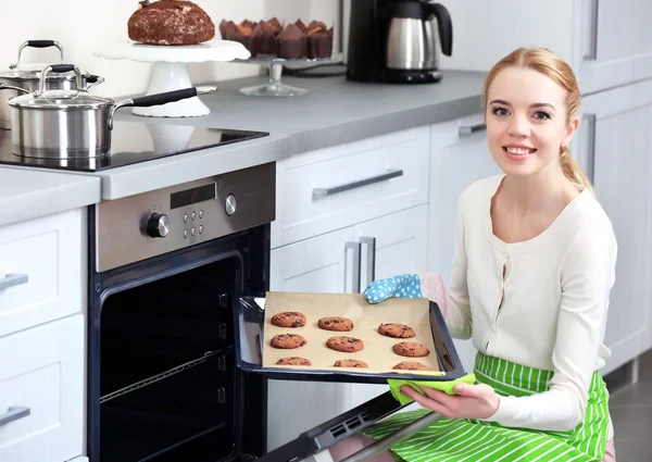 Young woman removing cookie tray — Stock Photo, Image