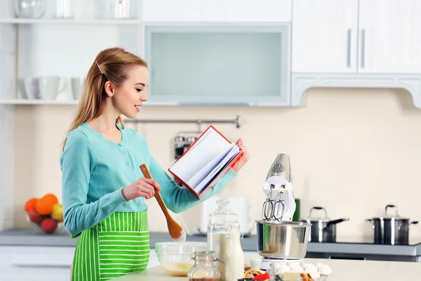 Mujer usando un cuaderno para seguir una receta — Foto de Stock