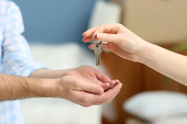 Női kéz, amely kulcsokat új lakás a férfi kéz homályos háttér — Stock Fotó