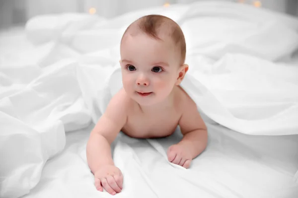 Entzückendes Baby auf weichem Bett liegend — Stockfoto
