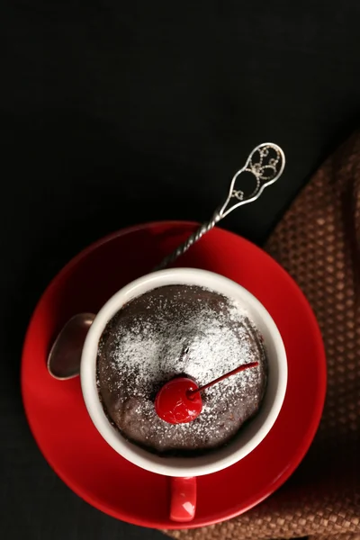 Pastel de chocolate en una taza roja con una cereza sobre un fondo de madera, vista superior — Foto de Stock