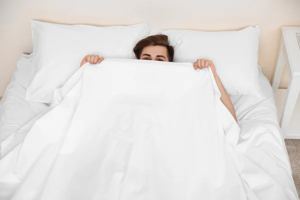 Uomo divertente sdraiato sotto coperta — Foto Stock