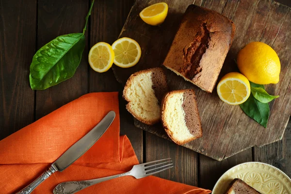 Delicious sweet cake bread with lemons on wooden cutting board, top view — Stock Photo, Image