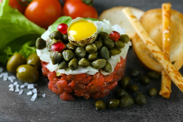 Biff tartar serveras med bröd pinnar på en grå yta, närbild — Stockfoto