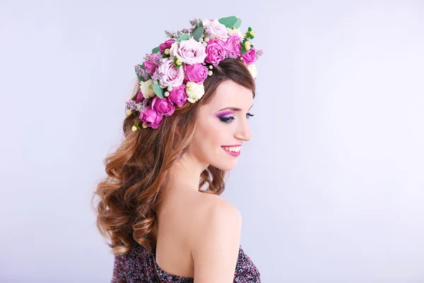 Όμορφη νεαρή γυναίκα που φοράει floral στήριγμα κεφαλής σε γκρι φόντο — Φωτογραφία Αρχείου
