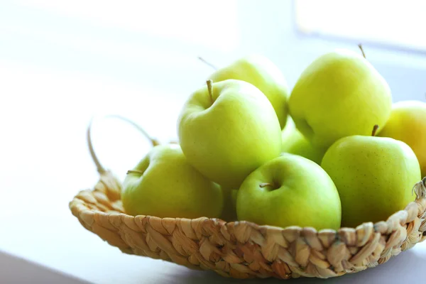 Ripe green apples in a wicker basket on windowsill — Stock Photo, Image