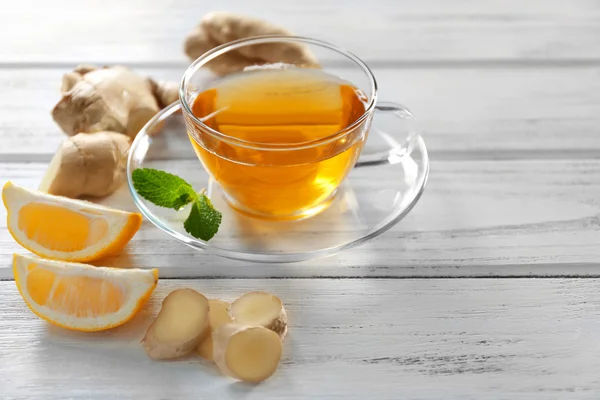 Glass cup of green tea with lemon and ginger root on wooden background — Stock Photo, Image