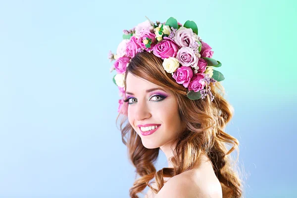 Mulher bonita vestindo headband floral em um fundo azul — Fotografia de Stock