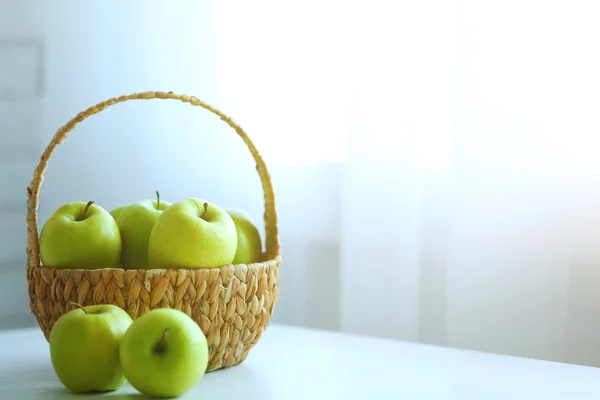 Maçãs verdes maduras em cesta em uma mesa de cozinha — Fotografia de Stock