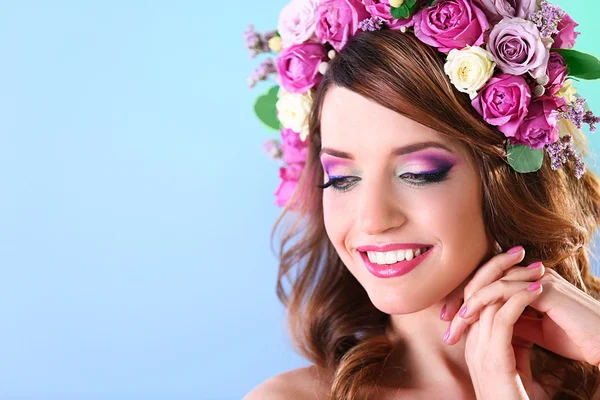 Hermosa mujer joven con diadema floral sobre un fondo azul — Foto de Stock