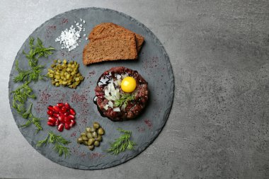 Lezzetli biftek tartare koyu arka plan üzerinde malzemelerle