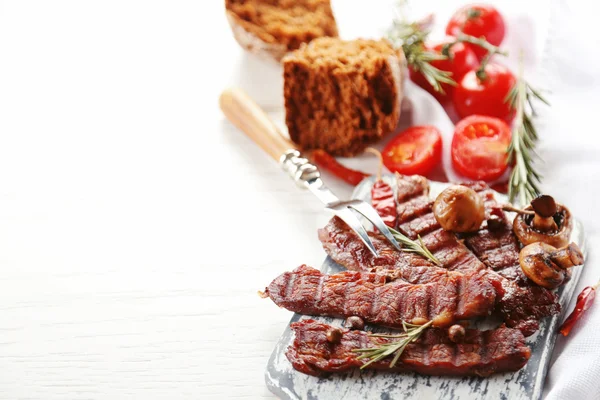 Carne grelhada com legumes na tábua de corte — Fotografia de Stock