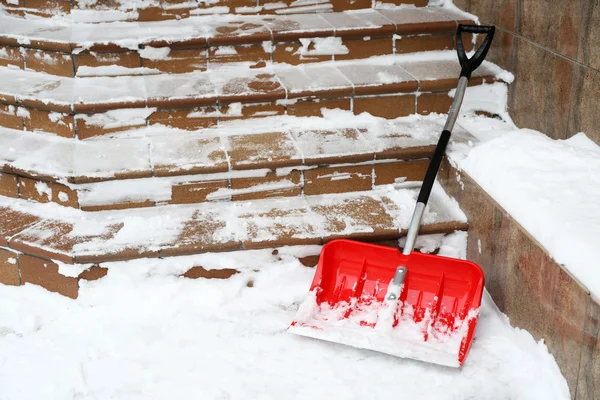 Red shovel for snow removal beside stairs — Stock Photo, Image