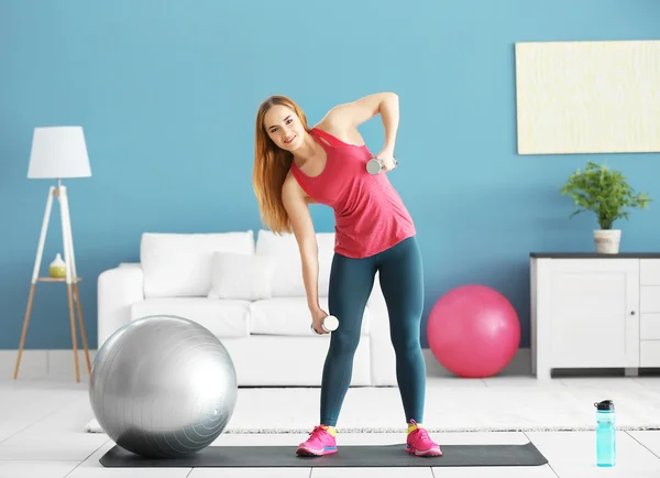 Sportswoman with dumbbells and bottle of water — Stock Photo, Image