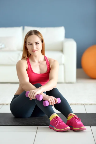 Sportlerin sitzt mit Hanteln — Stockfoto