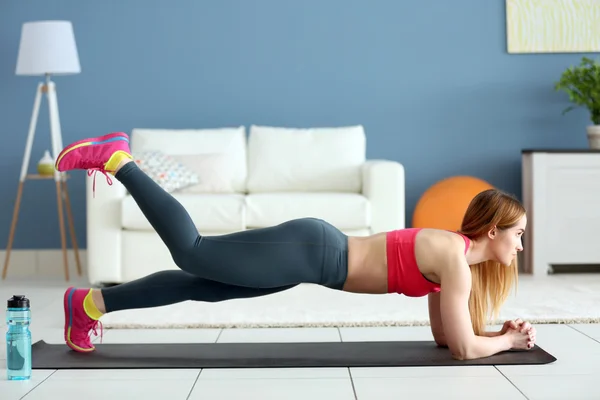 Sportvrouw doen oefeningen op een mat — Stockfoto