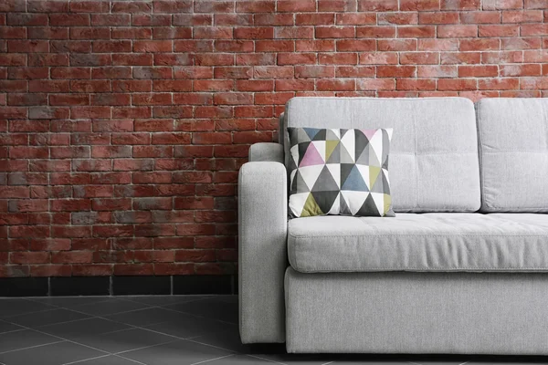 Sofá gris contra pared de ladrillo — Foto de Stock