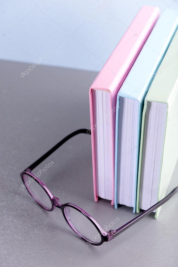 Books and eyeglasses on grey table 