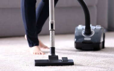 Kadın elektrikli süpürge kullanıyor.